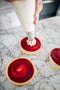 chantilly cream piped onto raspberry jelly tarts made fresh by tartlet bakery