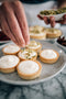 garnishing crushed pistachios over white chocolate and mascarpone tarts made fresh by tartlet bakery